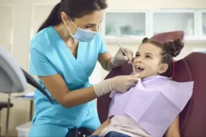 Why Early Dental Care With A Pediatric Dentist Matters For Your Child’s Growth Pediatric dentist examining a smiling child during a dental check-up, emphasizing early dental care and comfort for young patients.