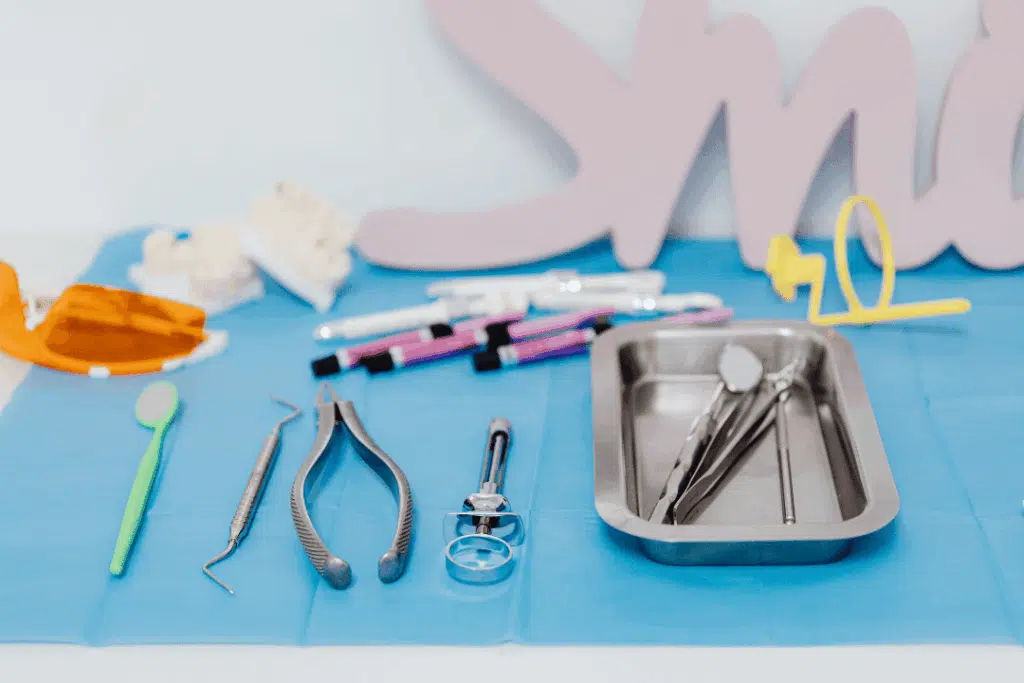 Dental Emergencies 101: What To Do When Your Child Chips, Cracks, Or Loses A Tooth (Before You Call The Dentist) Dental tools arranged on a blue surface, including pliers, mirrors, and cleaning instruments, relevant for pediatric emergency dental care.