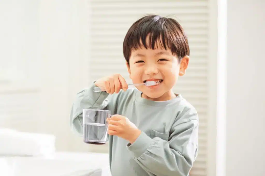 From Thumb-Sucking To Tongue Thrust: How Habits Shape Your Child’s Smile And What To Do About It Kid Holding A Toothbrush For Healthier Teeth