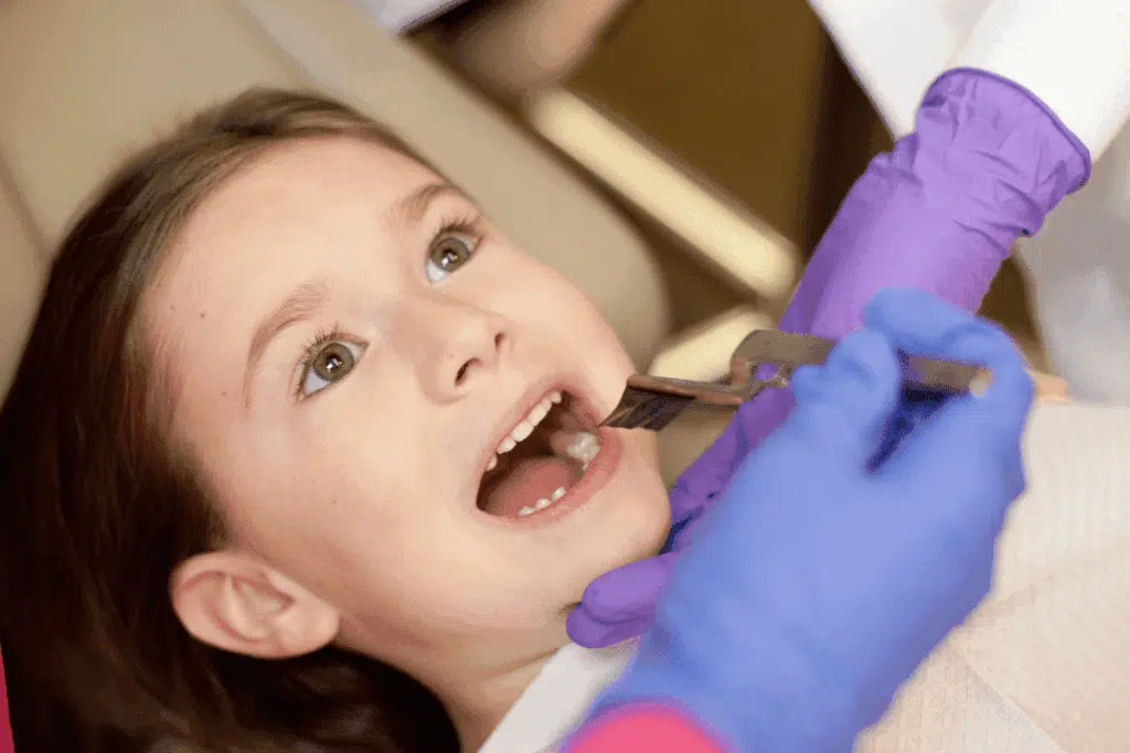 How Orthodontists Determine The Right Age For A Child’s First Orthodontic Visit Child undergoing orthodontic assessment with a caliper for bite alignment evaluation during a dental visit.