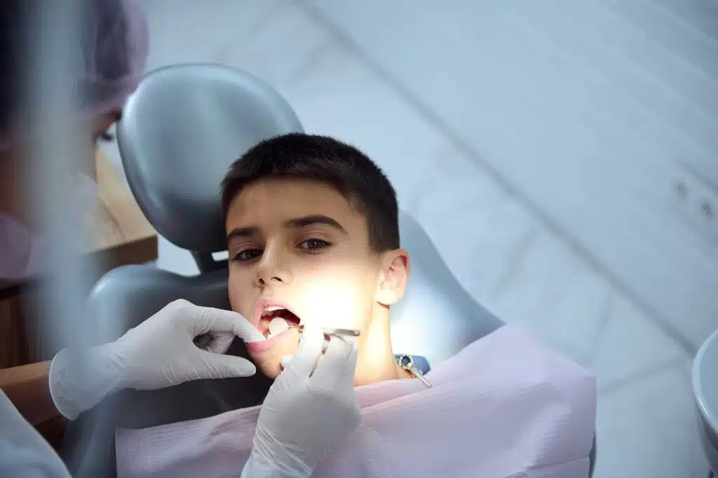 Can I Switch Orthodontists During Treatment? What You Need To Know Overhead View Of Pediatric Dentist Examining Oral Cavity Of A Teenage Boy